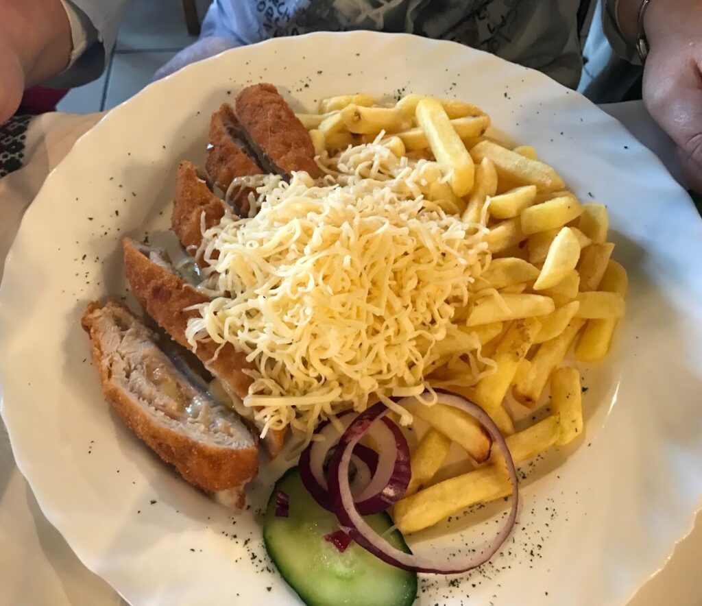 Sajttal töltött rántott hús sült krumplival és friss zöldségekkel.